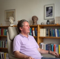 Picture: Thomas Abel is sitting in an armchair in his practice in front of a bookshelf and under a picture of Sigmund Freud